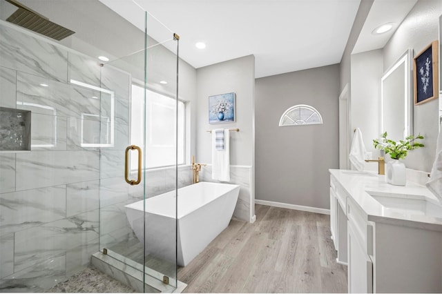 bathroom with double vanity, a marble finish shower, visible vents, a soaking tub, and wood finished floors