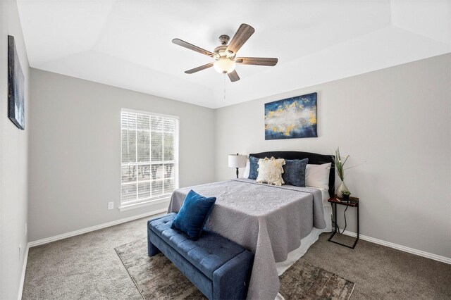 carpeted bedroom with a ceiling fan, a tray ceiling, and baseboards