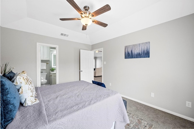 bedroom with visible vents, baseboards, a tray ceiling, carpet, and ensuite bath