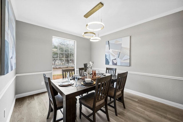 dining room with crown molding, baseboards, and wood finished floors