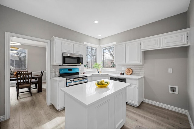 kitchen with a sink, white cabinets, light countertops, appliances with stainless steel finishes, and decorative backsplash