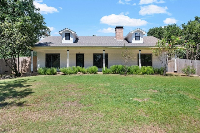 view of front of property with brick siding, a front lawn, a chimney, and fence