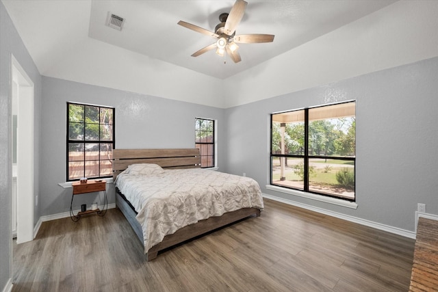 bedroom with ceiling fan, wood finished floors, visible vents, and baseboards