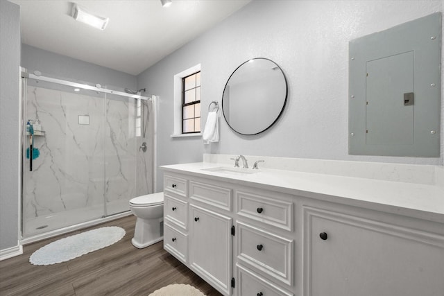 full bath featuring toilet, a marble finish shower, wood finished floors, and electric panel