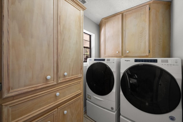 laundry room with cabinet space, a textured ceiling, and separate washer and dryer