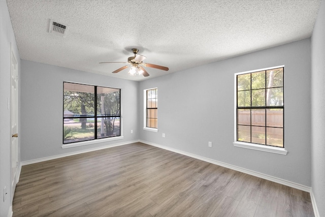 empty room featuring visible vents, ceiling fan, baseboards, and wood finished floors