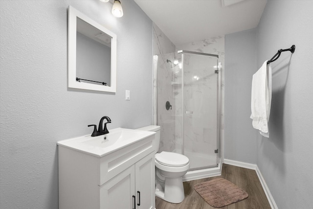 full bathroom with a marble finish shower, baseboards, toilet, wood finished floors, and vanity