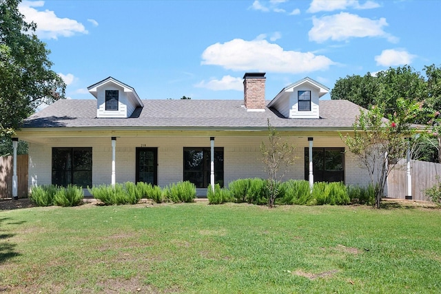 view of front of house with a front yard, a chimney, fence, and brick siding