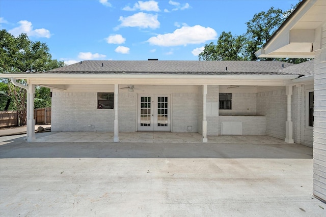 rear view of house featuring a shingled roof, brick siding, fence, a ceiling fan, and french doors