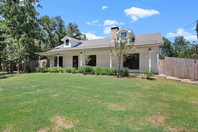 view of front facade with brick siding, a chimney, fence, and a front yard