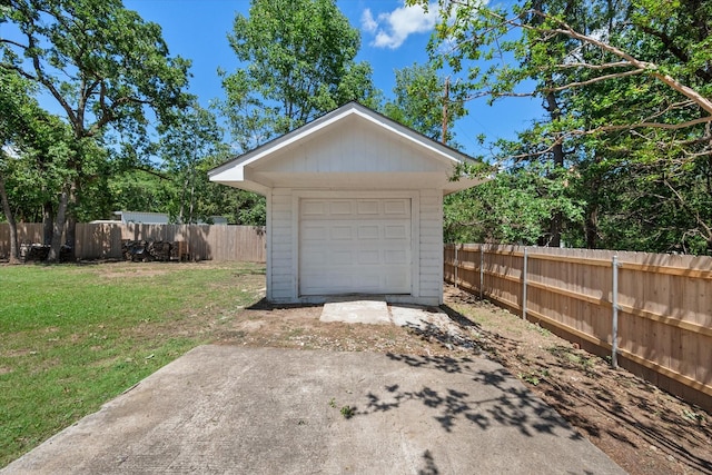 detached garage with driveway, a storage shed, and fence