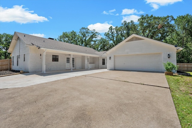 single story home featuring an attached garage, brick siding, fence, driveway, and french doors