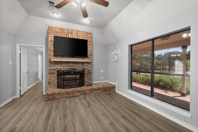 unfurnished living room with visible vents, lofted ceiling, wood finished floors, a textured ceiling, and a brick fireplace