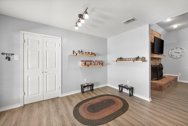 living area featuring visible vents, a fireplace, baseboards, and wood finished floors