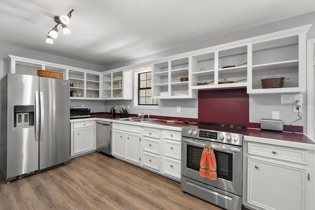 kitchen featuring open shelves, appliances with stainless steel finishes, white cabinets, a sink, and wood finished floors