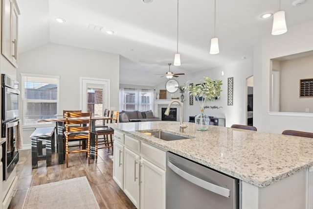 kitchen featuring a sink, plenty of natural light, dishwasher, and a glass covered fireplace