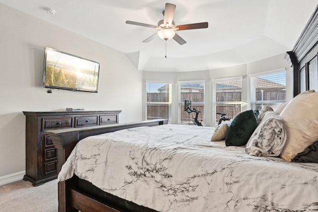 bedroom featuring baseboards, ceiling fan, a tray ceiling, and light colored carpet