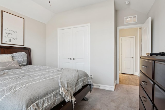 bedroom featuring visible vents, vaulted ceiling, a closet, and light colored carpet