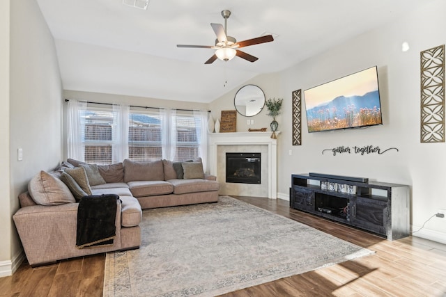 living area featuring a fireplace, lofted ceiling, visible vents, wood finished floors, and baseboards