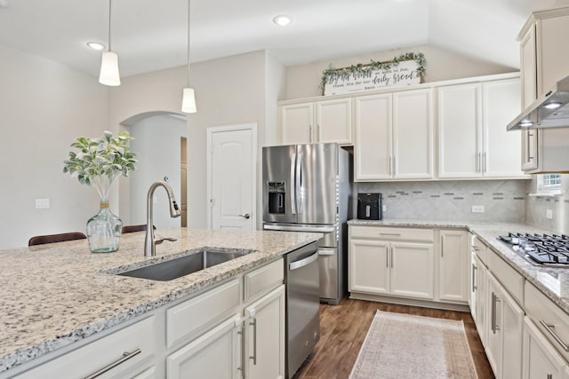 kitchen with tasteful backsplash, appliances with stainless steel finishes, dark wood-type flooring, wall chimney range hood, and a sink