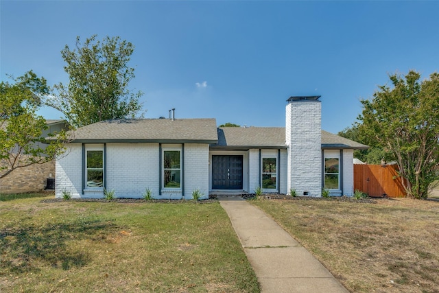 view of front of property featuring a front yard, a chimney, fence, and brick siding