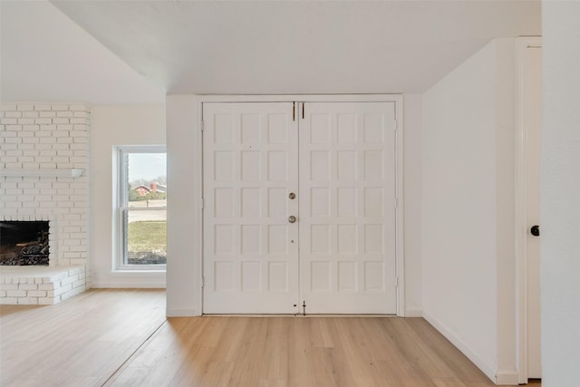 entrance foyer with baseboards, a fireplace, and light wood finished floors