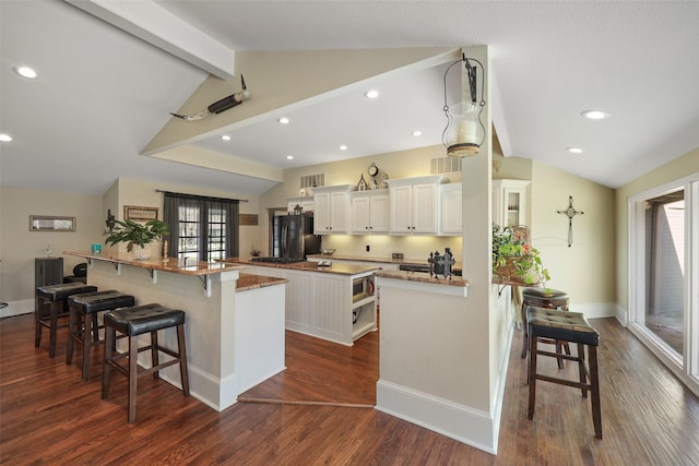 928 N Irving Heights Dr, Irving, TX 75061 - kitchen featuring vaulted ceiling with beams, a spacious island, stainless steel microwave, freestanding refrigerator, and a kitchen bar