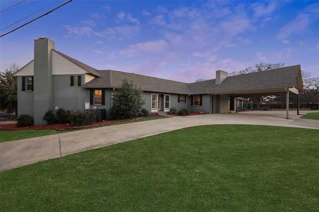 view of front of property with concrete driveway, a chimney, an attached carport, central air condition unit, and a front yard