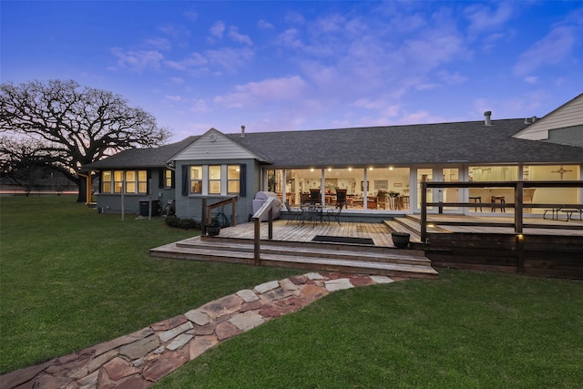 928 N Irving Heights Dr, Irving, TX 75061 - back of property at dusk with roof with shingles, outdoor dining space, a lawn, and a wooden deck