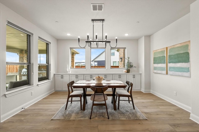 dining room featuring a chandelier, light wood-type flooring, visible vents, and baseboards