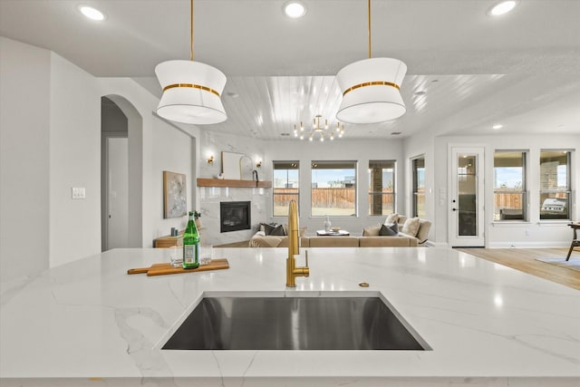 kitchen featuring open floor plan, a premium fireplace, a sink, and recessed lighting