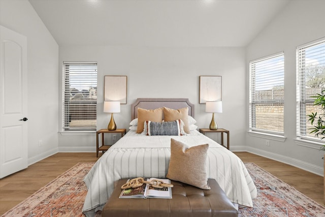 bedroom with lofted ceiling, wood finished floors, and baseboards