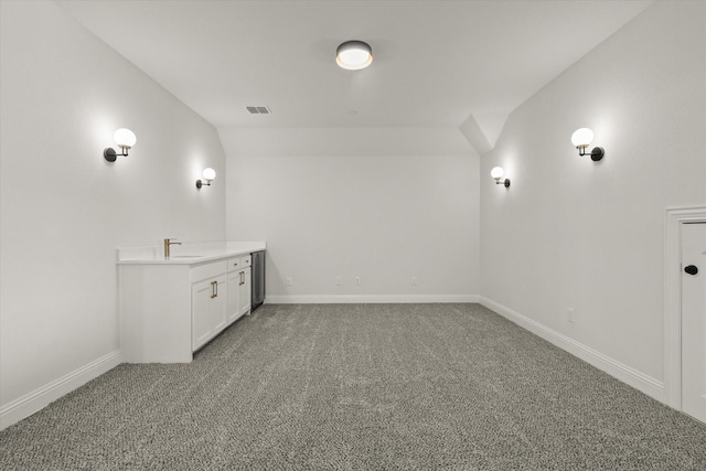 bathroom with vaulted ceiling, a sink, visible vents, and baseboards