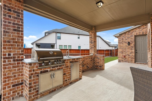 view of patio / terrace with exterior kitchen, a fenced backyard, a sink, and area for grilling