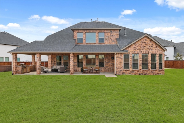 back of house with roof with shingles, brick siding, a patio, fence, and exterior kitchen