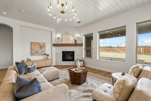 living area with visible vents, arched walkways, wood ceiling, wood finished floors, and a high end fireplace