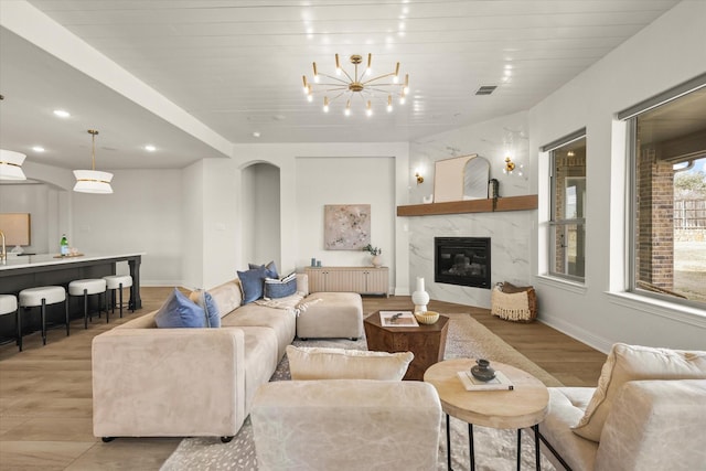 living area featuring arched walkways, light wood-style flooring, a fireplace, visible vents, and radiator