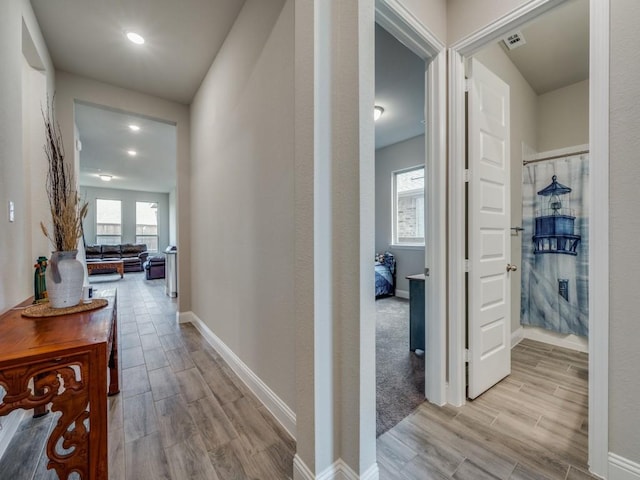 hallway featuring wood finish floors, visible vents, and baseboards