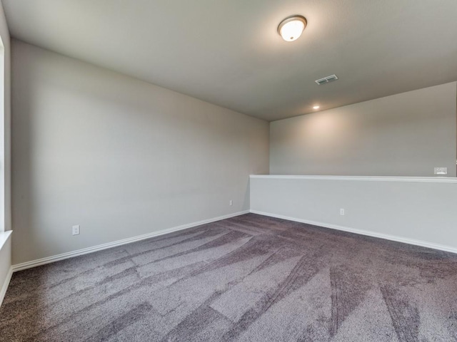 unfurnished room with baseboards, visible vents, and dark colored carpet