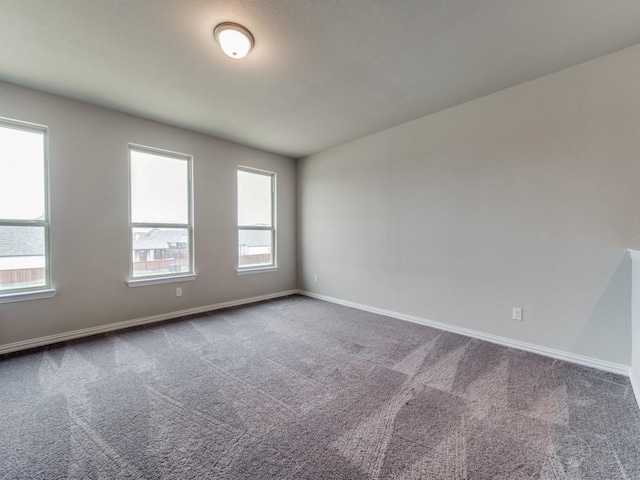 empty room with baseboards and dark carpet