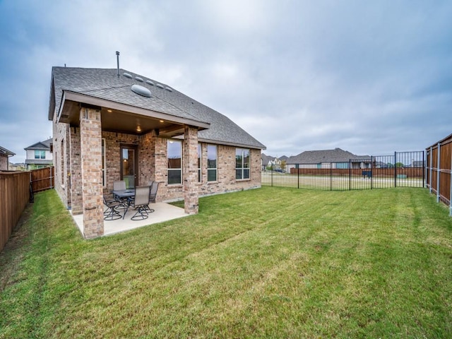 rear view of house with a patio area, a fenced backyard, brick siding, and a lawn