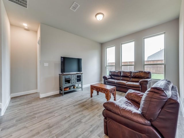 living room featuring visible vents, light wood-style flooring, and baseboards