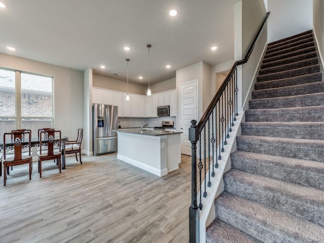 kitchen featuring light wood-style flooring, stainless steel appliances, white cabinetry, backsplash, and recessed lighting