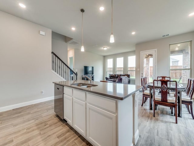 kitchen with visible vents, dishwasher, hanging light fixtures, light wood-type flooring, and a sink