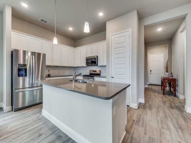 kitchen featuring light wood-style flooring, stainless steel appliances, a sink, visible vents, and decorative backsplash