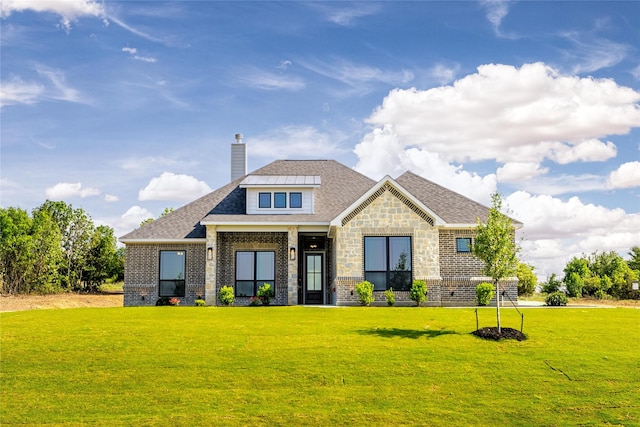 view of front of house featuring stone siding, a chimney, roof with shingles, a front yard, and brick siding