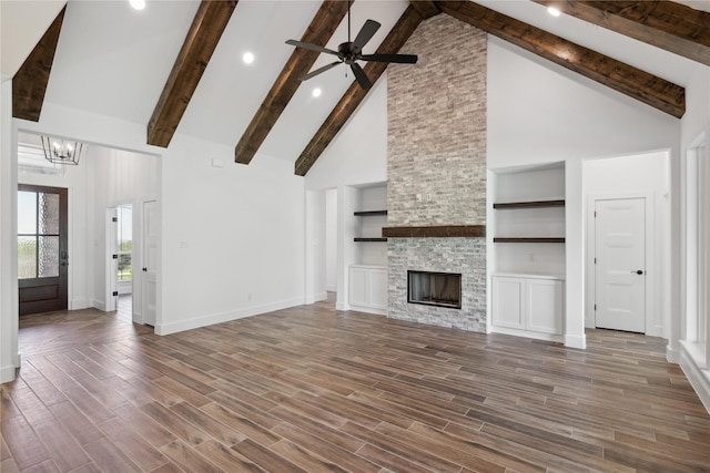 unfurnished living room with ceiling fan with notable chandelier, a fireplace, wood finished floors, and baseboards