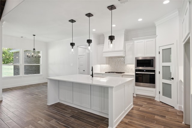 kitchen featuring a sink, built in microwave, stovetop, premium range hood, and backsplash