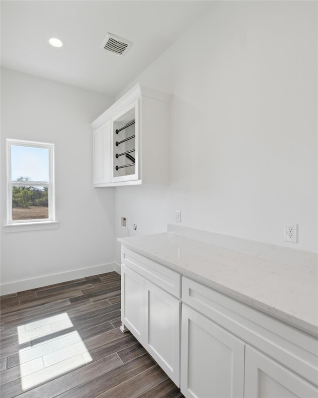 clothes washing area featuring cabinet space, baseboards, visible vents, hookup for a washing machine, and wood finish floors