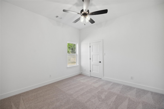 empty room with visible vents, baseboards, ceiling fan, and light colored carpet